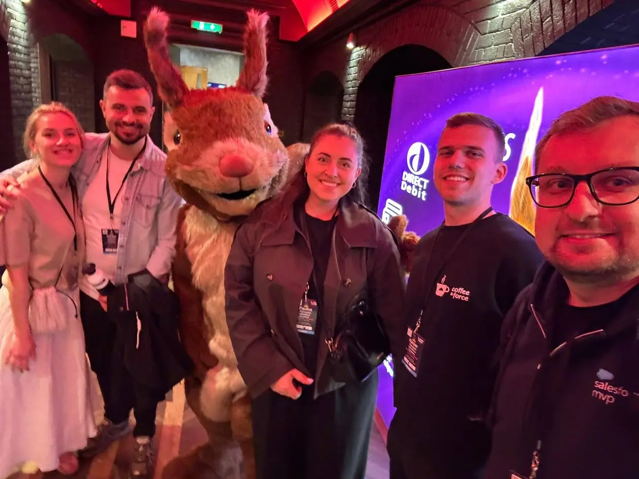 Grupa ludzi pozująca z dużą maskotką zająca w zamkniętej przestrzeni.